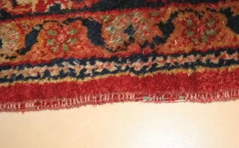 Before repair: Carpet with frayed and damaged edges.