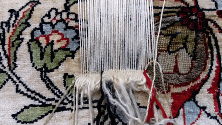 Hereke silk carpet hole repair in progress, showing intricate hand-knotting