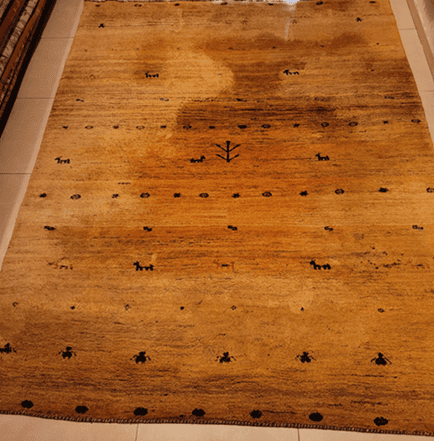 Heavily stained persian rug before professional deep cleaning in brussels .