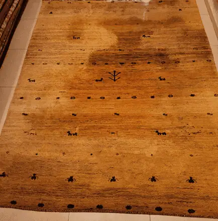 Heavily stained persian rug before professional deep cleaning in brussels .