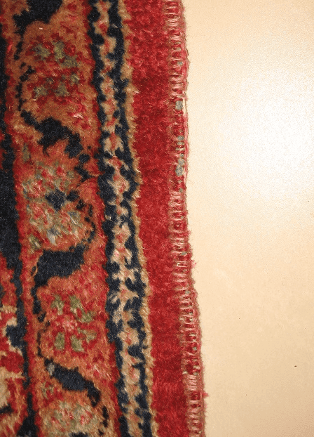 Worn carpet with severely frayed sides requiring professional edge repair.