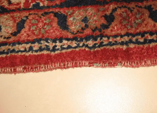 Worn carpet with severely frayed sides requiring professional edge repair.